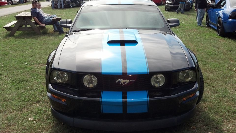 Black 2007 Ford Mustang with twin blue racing stripes on the hood and front grille