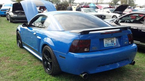2007 Ford Mustang - A blue Ford Mustang is parked on grass with other vehicles around it.
