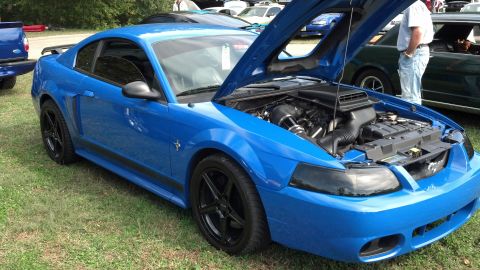 2007 Ford Mustang - A blue 2007 Ford Mustang is displayed with its hood open, revealing the engine bay and black aftermarket wheels.