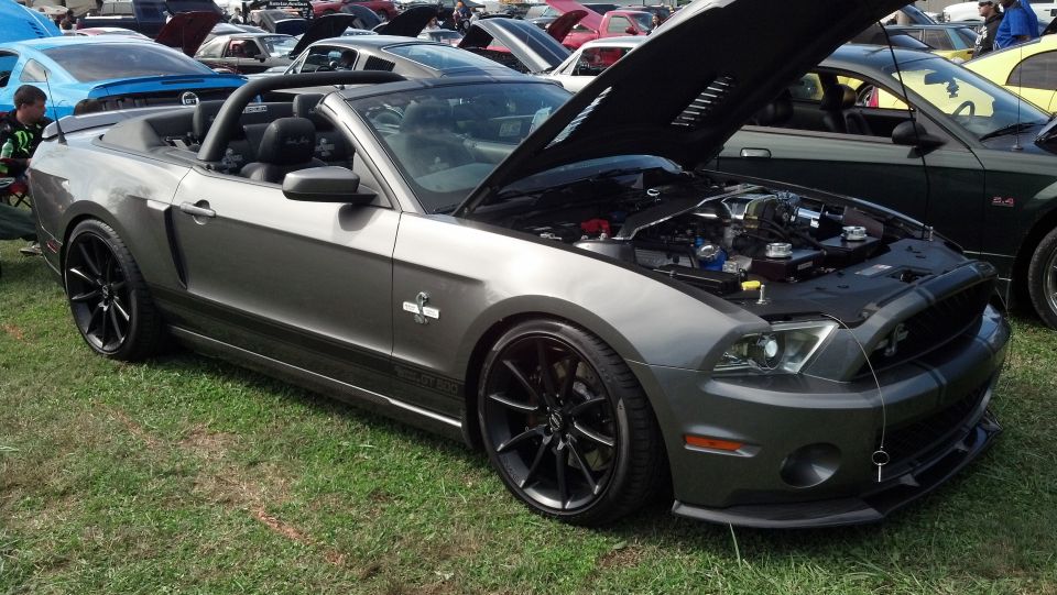 Gray convertible Mustang with hood open, showing engine. Black wheels, black racing stripes on hood and trunk