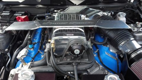 2007 Ford Mustang - Close-up view of a modified engine bay, a prominent supercharger and custom blue components.