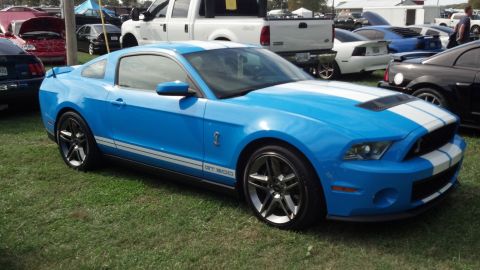 2007 Ford Mustang - Blue 2007 Ford Mustang GT500 with white stripes parked on grass at an outdoor event.