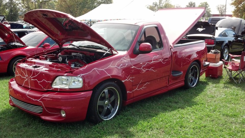 Red pickup truck with lightning bolt graphics, hood and trunk open