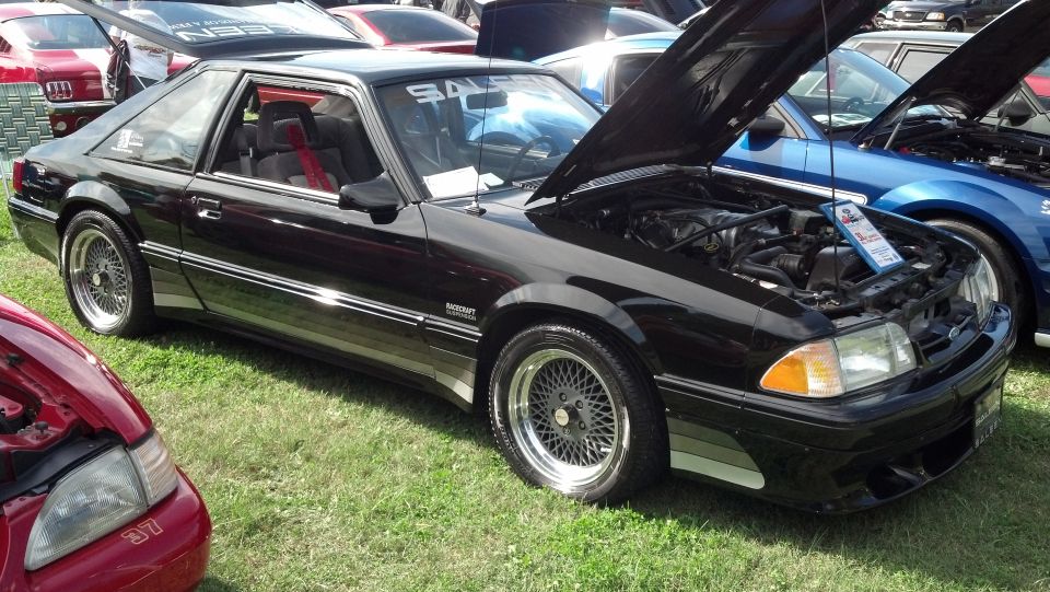 Black Saleen Mustang with hood open, mesh wheels, and body kit
