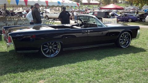 2007 Ford Mustang - A classic black convertible with custom wheels sits on display at an outdoor event.