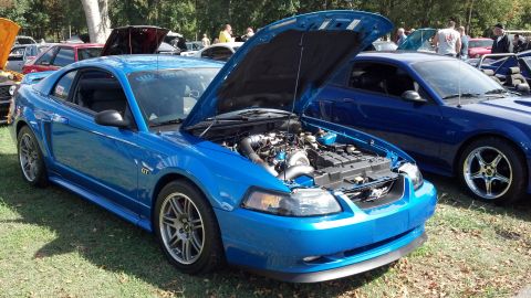 2007 Ford Mustang - A blue 2007 Ford Mustang GT is displayed with its hood open, parked on grass next to another blue Mustang.