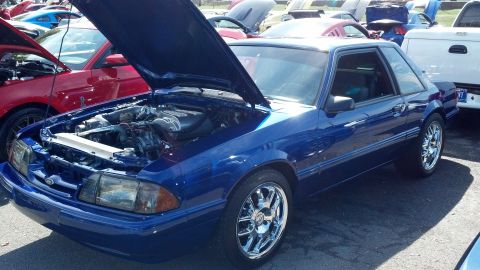 2007 Ford Mustang - A blue 1987 Ford Mustang coupe is displayed with its hood open, revealing the engine bay, at an outdoor car show.