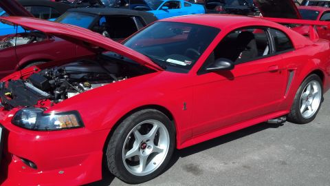 2007 Ford Mustang - A red Ford Mustang is parked with its hood open, revealing the engine compartment. Several other vehicles are visible in the background.