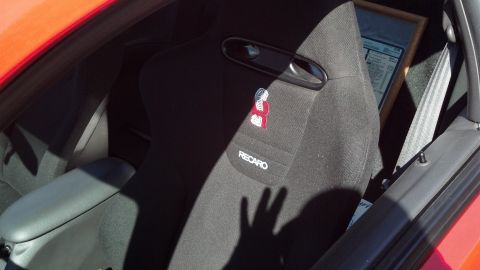 2007 Ford Mustang - Interior view of a red car's black Recaro seat, with a framed document in the background.