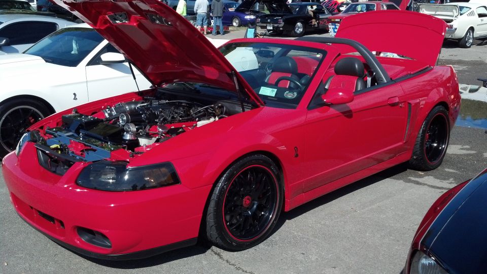 Red 2007 Ford Mustang convertible with hood and trunk open, showing engine and interior. Another white Mustang is parked nearby
