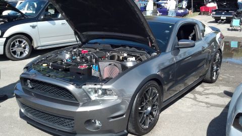 2007 Ford Mustang - A modified Ford Mustang is displayed with its hood up, revealing a supercharged engine and aftermarket air intake.
