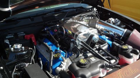 2007 Ford Mustang - Engine bay view of a supercharged V8 motor, likely from a Ford Mustang, with custom chrome and blue accents.