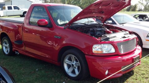 2007 Ford Mustang - A red Ford F-150 Lightning pickup truck is displayed with its hood open, parked outdoors on a grassy area.