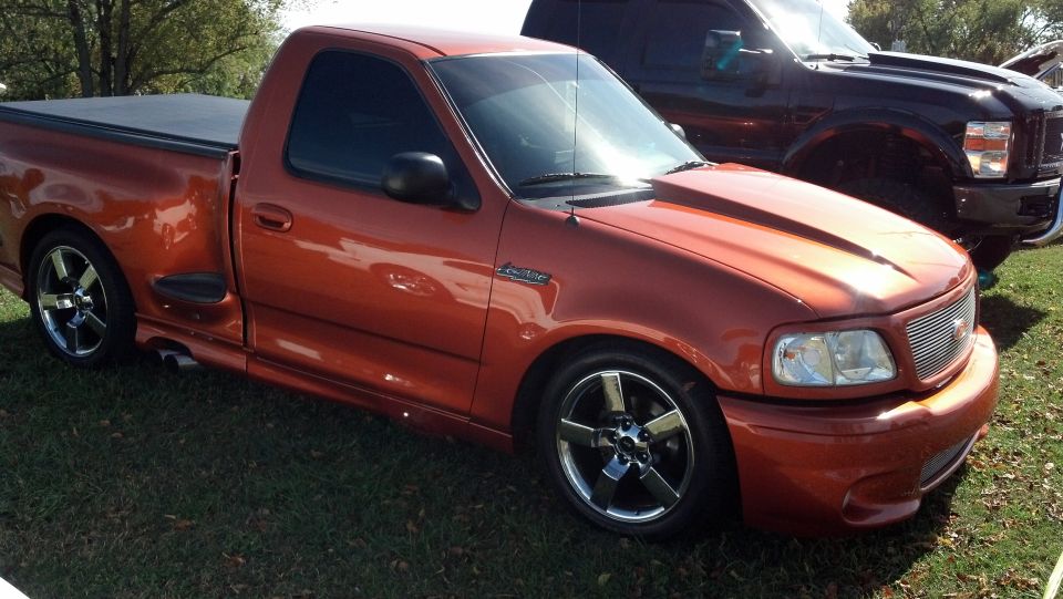 Orange Ford F-150 Lightning pickup truck with aftermarket wheels and hood scoop