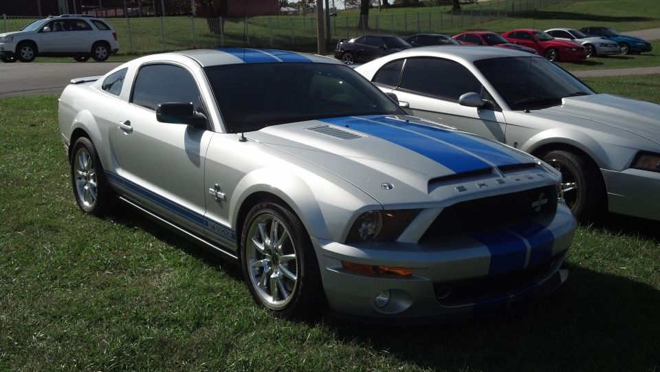 Silver 2007 Ford Mustang Shelby GT500 with blue stripes parked on grass