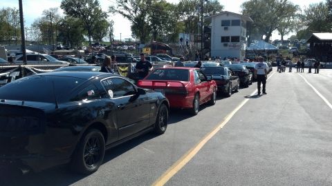 2007 Ford Mustang - A line of cars, including a black Ford Mustang, are staged at a drag racing event.