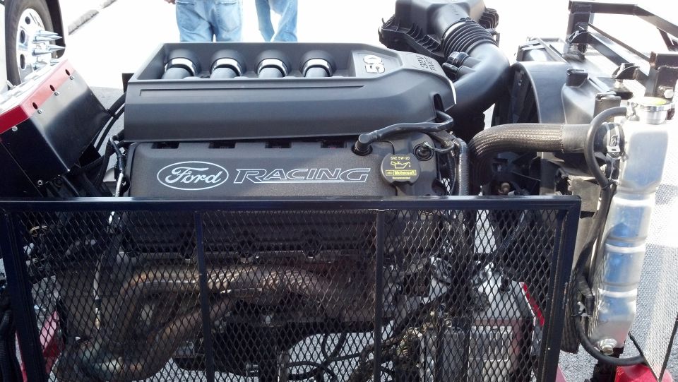 Close-up of a Ford Racing engine with a black intake manifold and silver valve covers