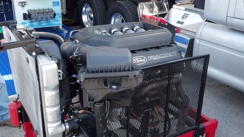 2007 Ford Mustang - A Ford Racing V8 engine is displayed with its intake manifold and radiator visible, likely at a car show or event.