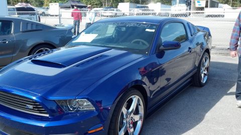 2007 Ford Mustang - A blue Ford Mustang with a ROUSH banner is parked next to another vehicle.