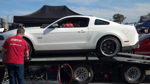 2007 Ford Mustang - A white Ford Mustang is loaded onto a trailer, with a man in a red shirt observing.