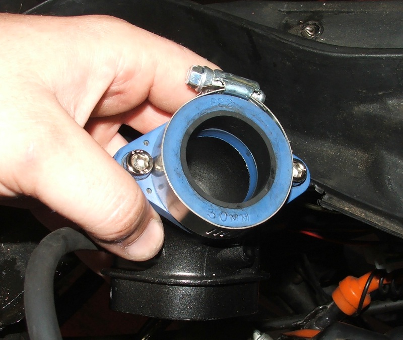 Hand holding a blue and black motorcycle intake manifold part with '30MM' visible