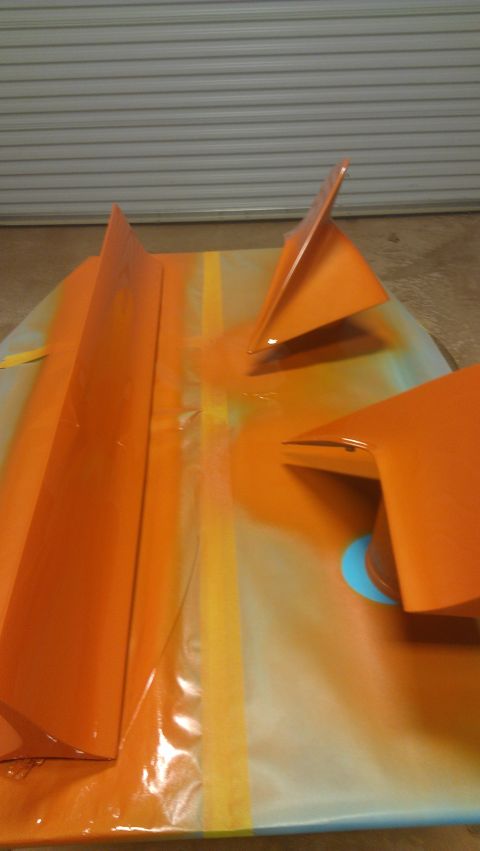 1973 Chevrolet Camaro - Car parts are being painted orange on a surface with a garage door visible behind them.