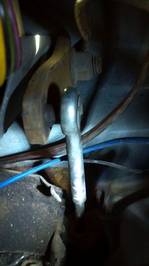 1986 Ford Bronco - A close-up view of a vehicle's clutch linkage mechanism, showing a metal rod and associated hardware.