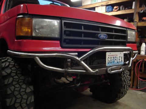 1989 Ford Bronco - Front view of a red 1980s Ford truck with a custom polished tubular steel front bumper, black grille with Ford emblem, and a Washington 'GO…