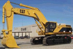 1991 Ford LTD Crown Victoria - A large yellow Caterpillar excavator is parked outdoors with a building and a few cars in the background.