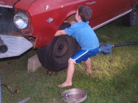 1966 Ford Ranchero - Young helper works on the front wheel of a 1966 Ford Ranchero.