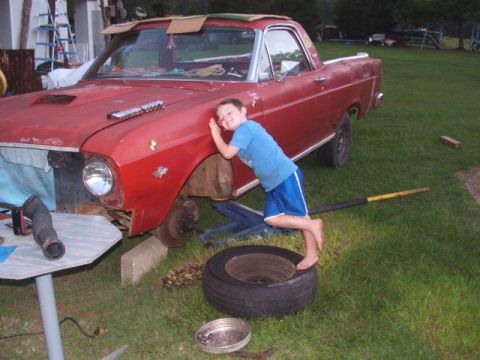 1966 Ford Ranchero - A child leans on the fender of a red 1966 Ford Ranchero that is undergoing repairs.