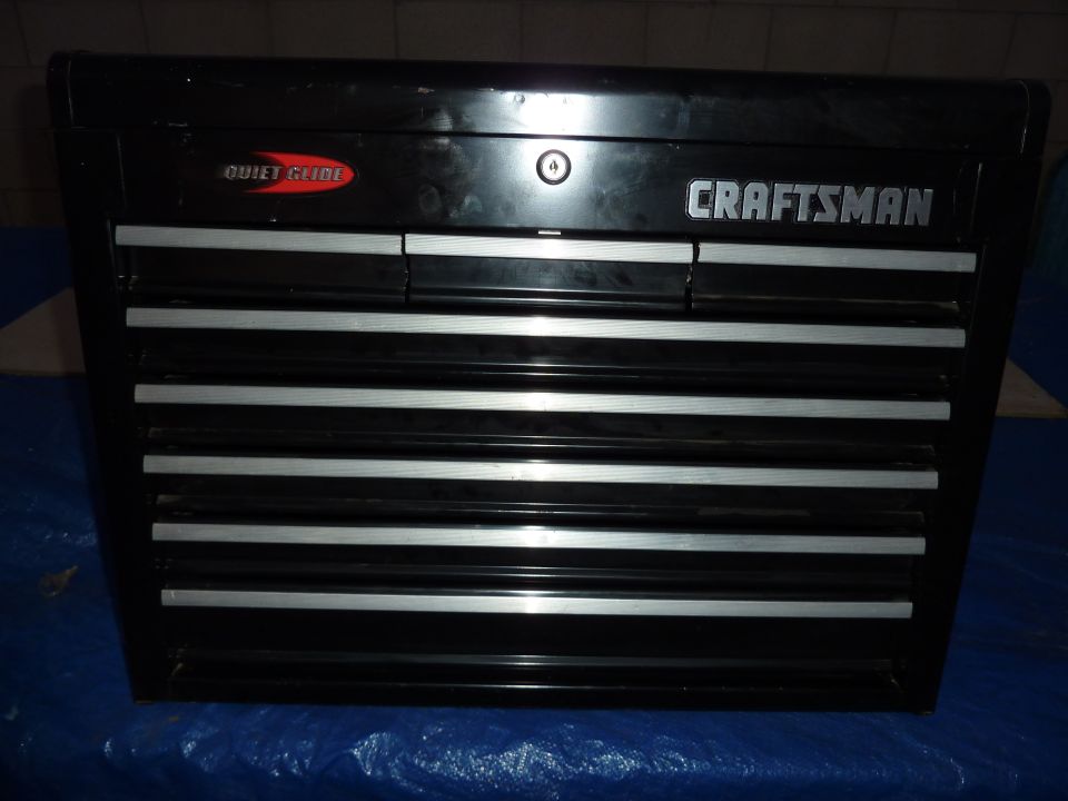Black Craftsman tool chest with silver drawer pulls and a red 'Quiet Glide' logo
