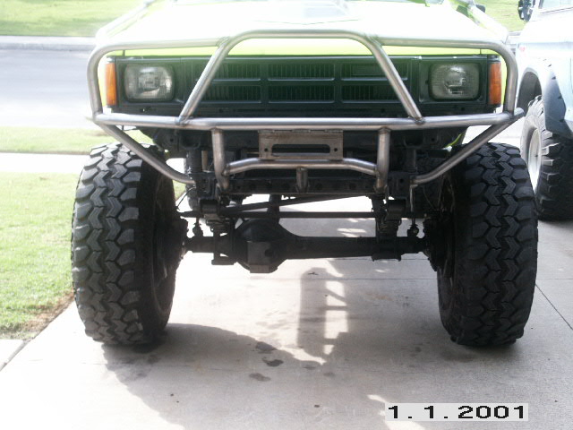 Front of lifted green Toyota pickup with tube bumper and large off-road tires