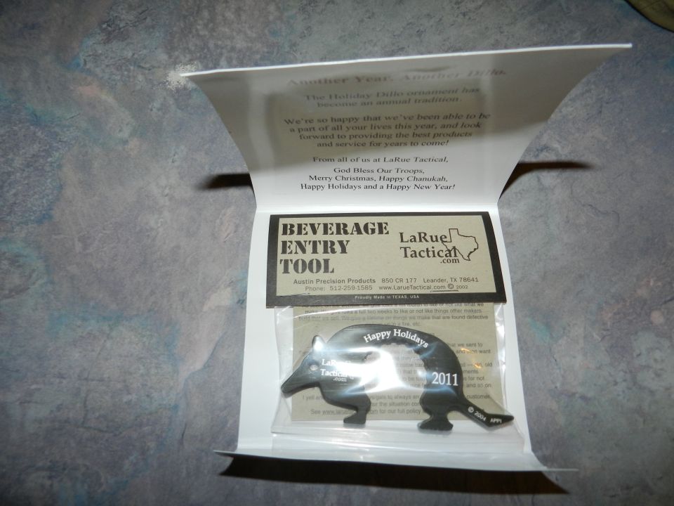 Black metal beverage entry tool shaped like an armadillo with 'Happy Holidays' and '2011' text