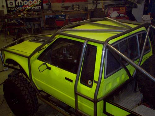 Neon green pickup cab with steel roll cage in a garage