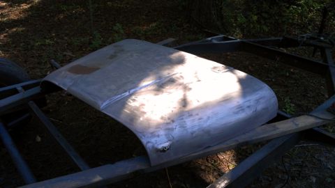 1978 Ford Bronco - A bare metal hood sits on a trailer frame, awaiting restoration or modification.