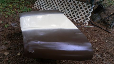 1978 Ford Bronco - A car door, possibly a Ford Bronco, is shown with primer and paint, lying on the ground.