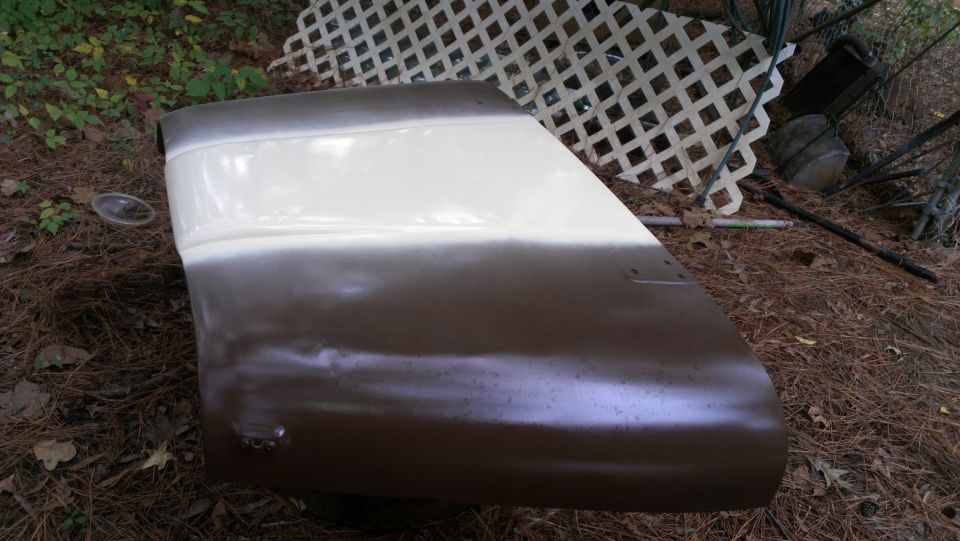 Brown and white car door, angled view, showing primer and paint. Some rust spots visible