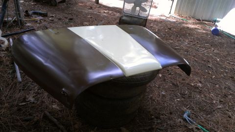 1978 Ford Bronco - This is a hood, possibly for a classic vehicle, resting on a stack of tires outdoors.