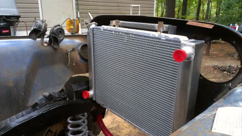 1978 Ford Bronco - A new radiator is being installed on a vehicle, showing the front chassis and suspension components.