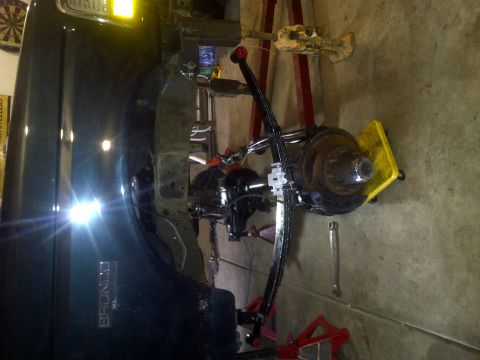 1995 Ford Bronco - The rear axle assembly of a Ford Bronco XL is shown undergoing maintenance in a garage setting.
