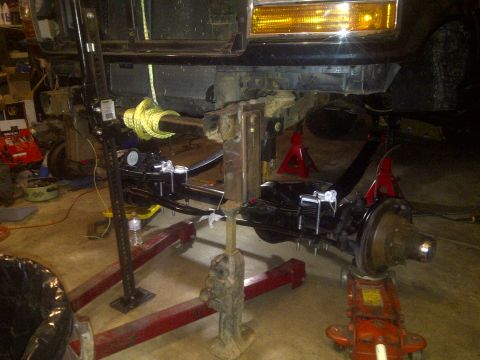 1995 Ford Bronco - The front suspension of a 1995 Ford Bronco is being worked on, supported by jack stands.