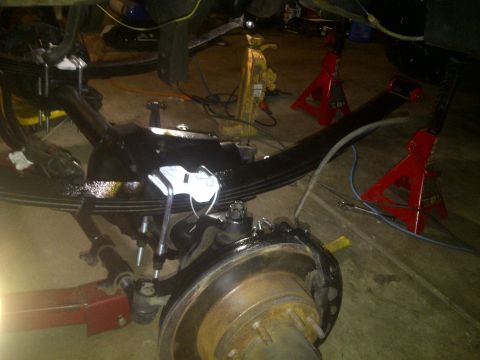 1995 Ford Bronco - Close-up view of vehicle suspension components, including a leaf spring and brake assembly, during maintenance.