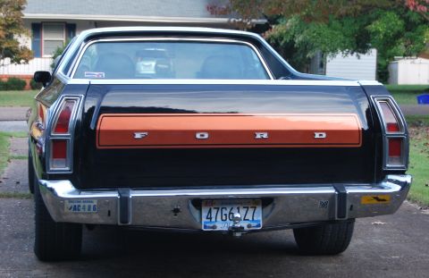 1975 Ford Ranchero - Rear view of a black Ford Ranchero with an orange tailgate stripe and chrome bumper.