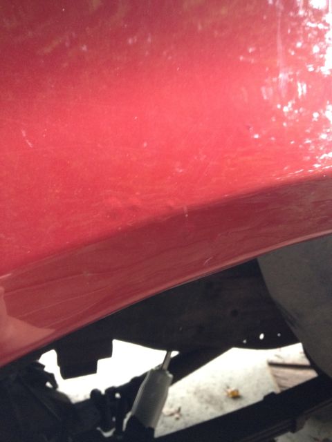 1996 Ford F-150 - Close-up view of a red truck's undercarriage, revealing suspension components and a shock absorber.