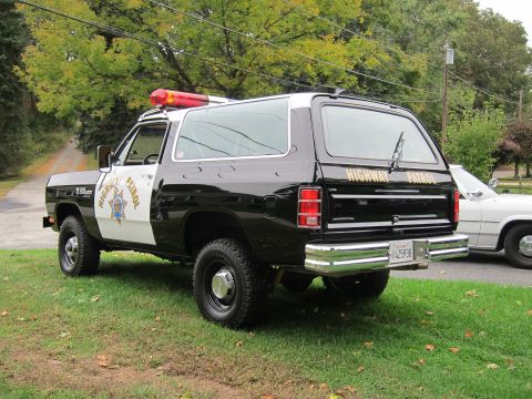 1987 Dodge 1500 - A black and white Dodge Ramcharger, marked as Highway Patrol, is parked on a grassy area next to another vehicle.