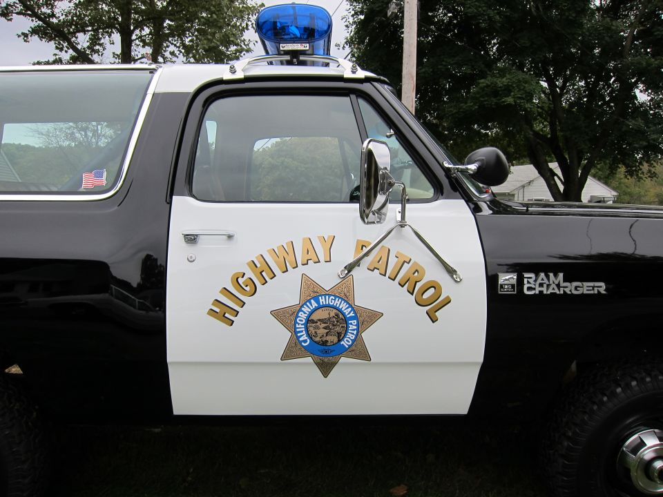 Side view of a black and white 1987 Dodge Ramcharger California Highway Patrol SUV with "HIGHWAY PATROL" text and badge on the door