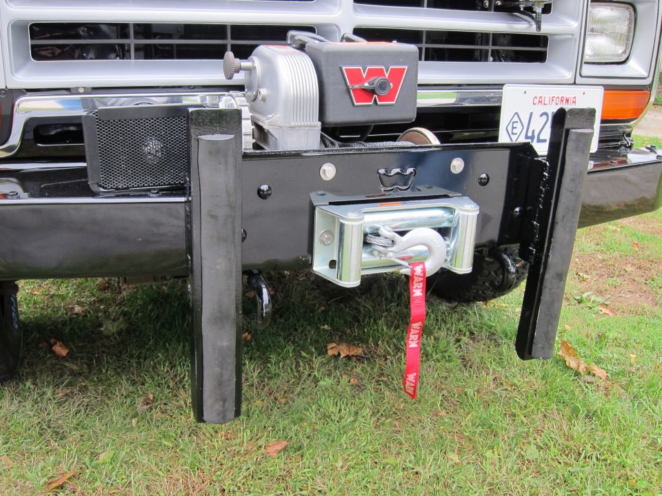 Truck front bumper with a WARN winch, red tow strap, and California license plate E42