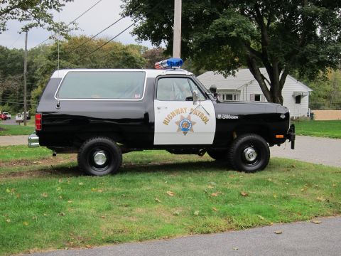 1987 Dodge 1500 - A side view of a black and white Dodge Ramcharger police vehicle parked on a grassy area.
