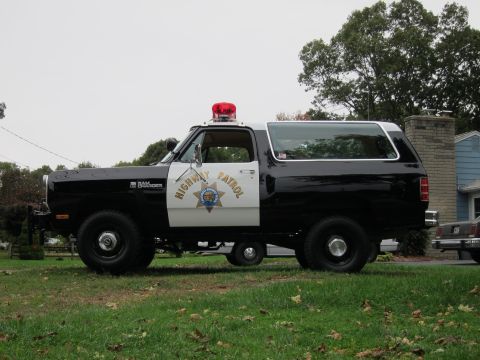 1987 Dodge 1500 - Side view of a black and white Dodge Ramcharger, marked as "HIGHWAY PATROL" with a light bar.